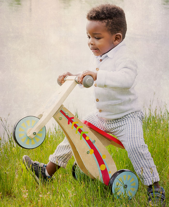 bambino con triciclo di legno