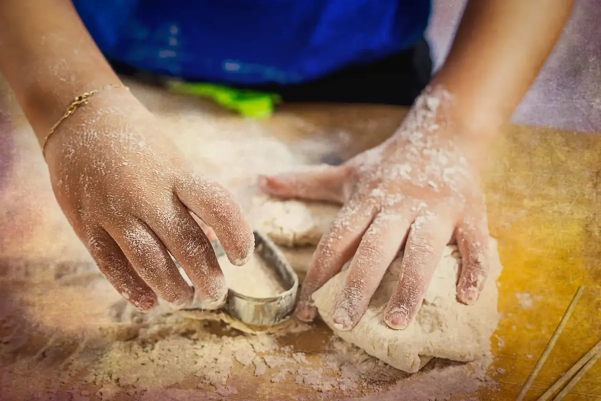 dettaglio di due mani di bambina che impastano un po' di pane