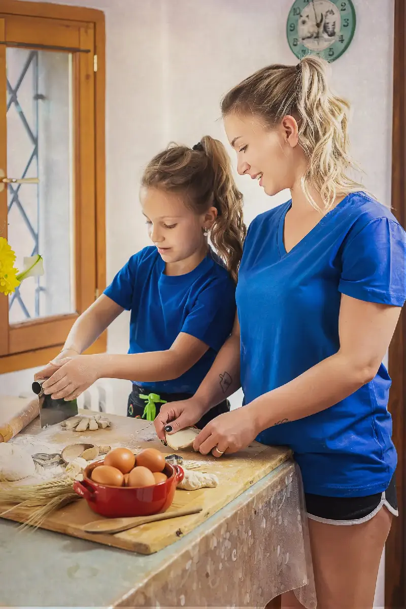 servizio fotografico mommyandme reggio emilia, madre e figlia con maglietta azzurra impastano del pane